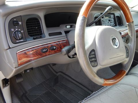 2002 Mercury Grand Marquis - The interior of a 2002 Mercury Grand Marquis shows wood grain accents on the dashboard and a leather-wrapped steering wheel.