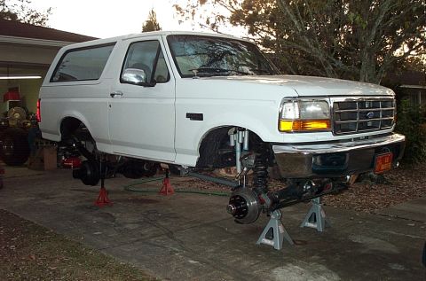 1995 Ford Bronco - White 1995 Ford Bronco undergoing maintenance with front end raised on jack stands.