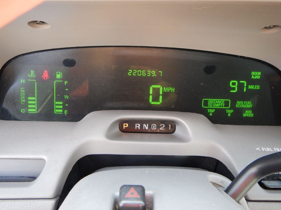 Car dashboard with digital displays for speed, fuel, and odometer. Shows 0 MPH and 220639.7 miles