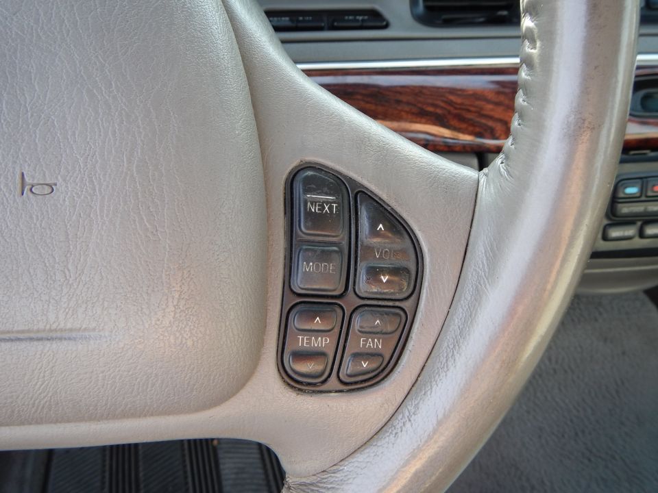 Close-up of steering wheel with buttons for NEXT, MODE, VOL, TEMP, and FAN