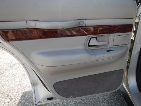2002 Mercury Grand Marquis - Interior door panel of a 2002 Mercury Grand Marquis, wood grain trim and a grey fabric lower section.