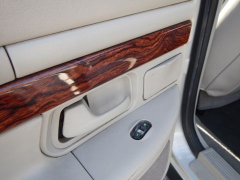 2002 Mercury Grand Marquis - The interior door panel features faux wood grain trim and a power window control switch.