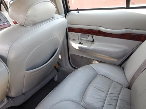 2002 Mercury Grand Marquis - Interior view of a car's rear seats and door panel, showing light gray leather and wood trim details.