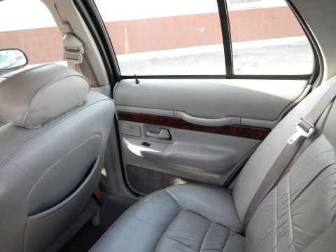 2002 Mercury Grand Marquis - The interior of a 2002 Mercury Grand Marquis features light gray leather seats and wood trim on the door panel.