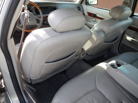 2002 Mercury Grand Marquis - The interior of a 2002 Mercury Grand Marquis is visible, with light gray leather seats and wood trim accents.