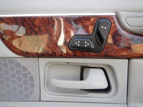 2002 Mercury Grand Marquis - Close-up of a car's interior door panel, showing wood grain trim, power seat adjustment buttons, and a door handle.