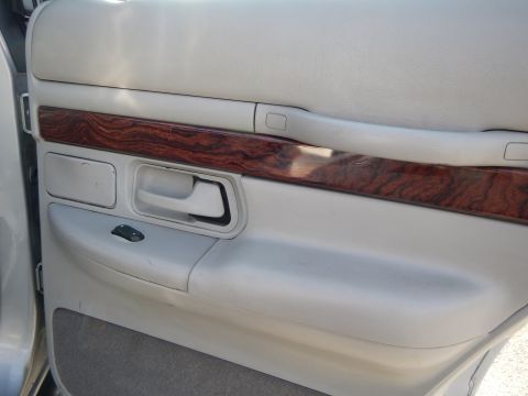 2002 Mercury Grand Marquis - The interior door panel of a 2002 Mercury Grand Marquis features faux wood trim and beige upholstery.