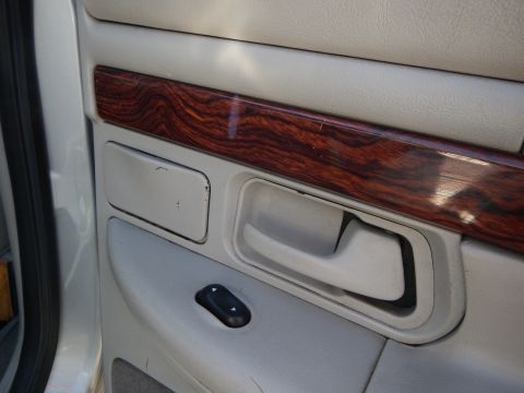 2002 Mercury Grand Marquis - Close-up of a car's interior door panel showing wood grain trim and a power window switch.