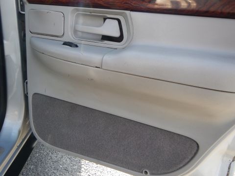 2002 Mercury Grand Marquis - Close-up of a car's interior door panel, showing the armrest, door handle, and wood trim accents.