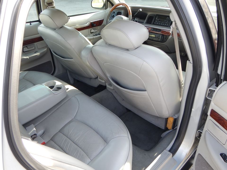 Light gray leather interior of a 2002 Mercury Grand Marquis, showing the rear seats, center console, and dashboard