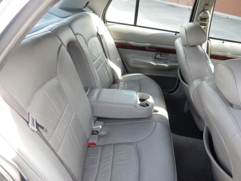 2002 Mercury Grand Marquis - The interior of a 2002 Mercury Grand Marquis features light-colored leather seats and a fold-down armrest with cup holders.