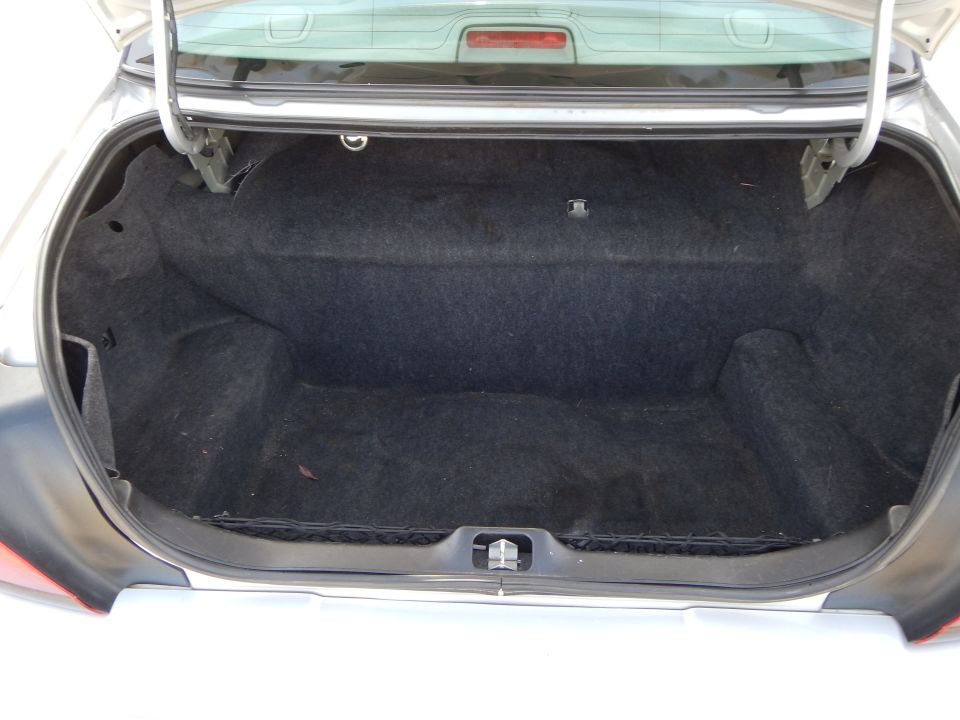 Open car trunk interior with black carpet lining and a cargo net