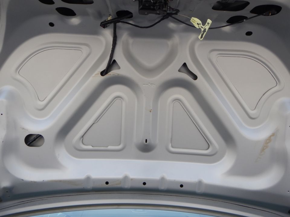 Underside of a car hood with stamped bracing and wiring harness