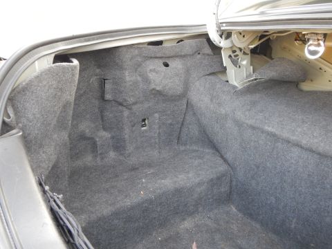 2002 Mercury Grand Marquis - The interior of a car trunk shows gray carpeting and the latch mechanism for the lid.