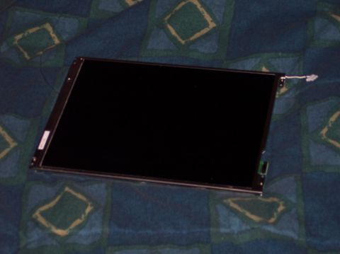1990 Ford Bronco - A detached car stereo screen is shown on a blue and green patterned surface.