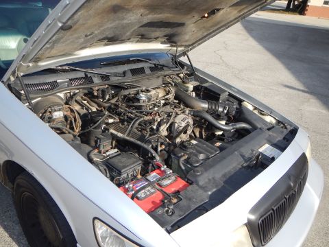 2002 Mercury Grand Marquis - The engine compartment of a silver 2002 Mercury Grand Marquis is shown with the hood raised.