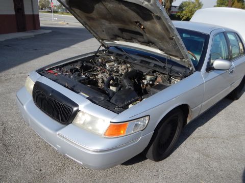 2002 Mercury Grand Marquis - A silver 2002 Mercury Grand Marquis is parked outside with its hood open, revealing the engine compartment.