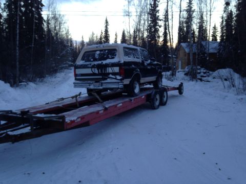 1993 Ford Bronco - A Ford Bronco is transported on a trailer through a snowy, wooded area.