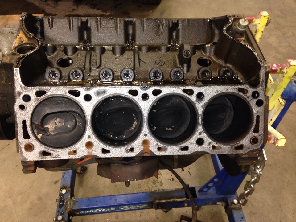 Engine block with four cylinders visible, on an engine stand
