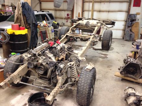 1993 Ford Bronco - The frame and powertrain components of a vehicle are disassembled in a workshop setting.