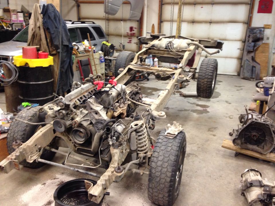 Truck chassis with engine and transmission removed, in a garage