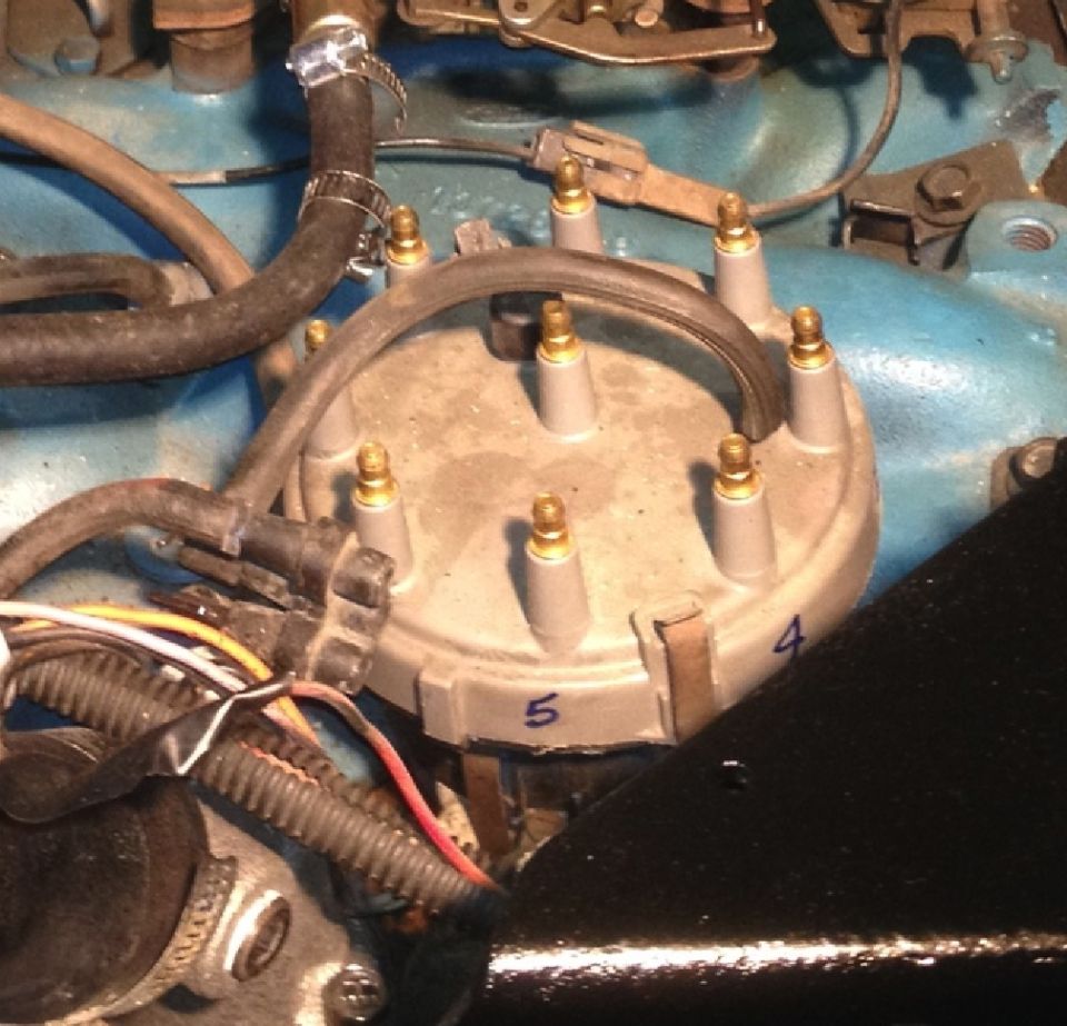 Close-up of a distributor cap with numbered spark plug wire terminals and associated wiring