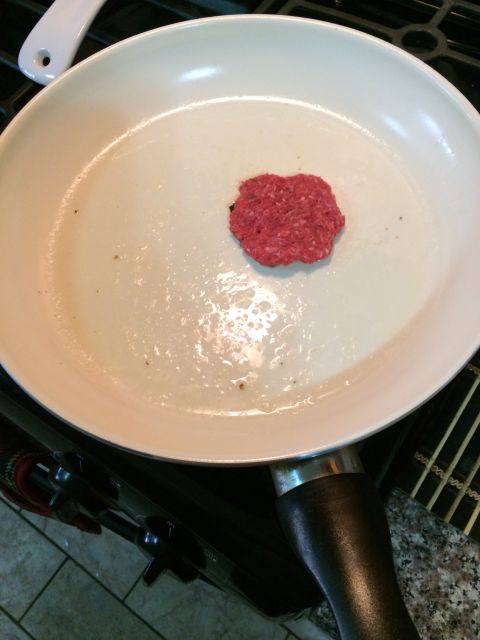 1968 Ford Mustang - A single raw hamburger patty sits in a white frying pan, ready to be cooked.