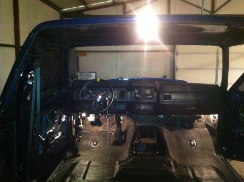 1982 Ford Bronco - The interior of a blue vehicle is shown, with the dashboard, steering wheel, and floor pans visible as it appears to be undergoing repairs.