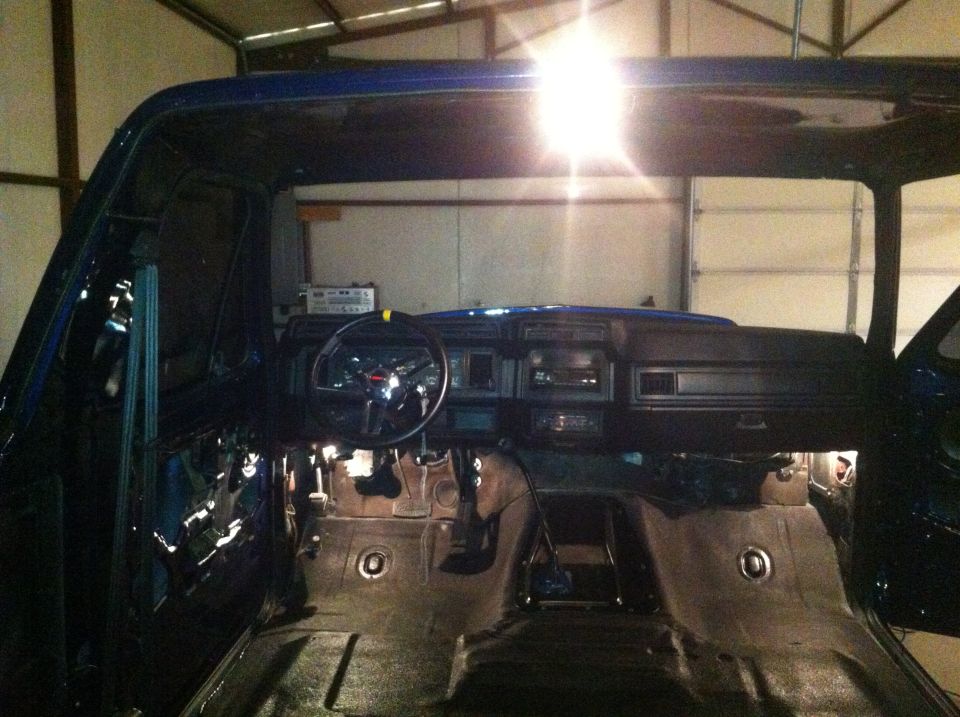 Interior of a blue vehicle with dashboard and steering wheel visible, undergoing repairs