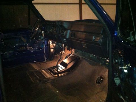 1982 Ford Bronco - Interior of a blue vehicle with dashboard and floor removed, showing steering wheel and transmission.