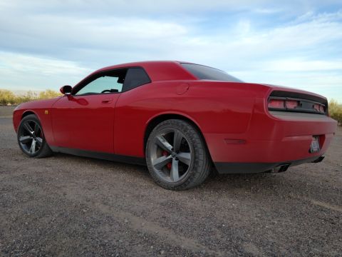 2010 Dodge Challenger - A red Dodge Challenger is parked on a dirt road under a cloudy sky.