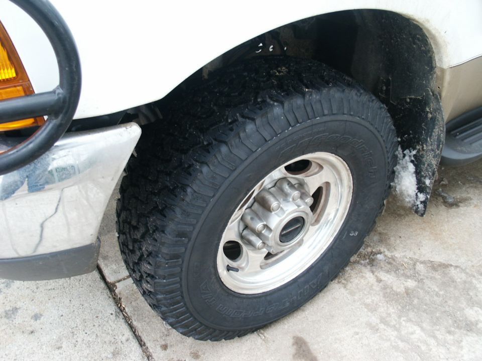 White 2000 Ford F-250 front wheel and chrome bumper, close-up