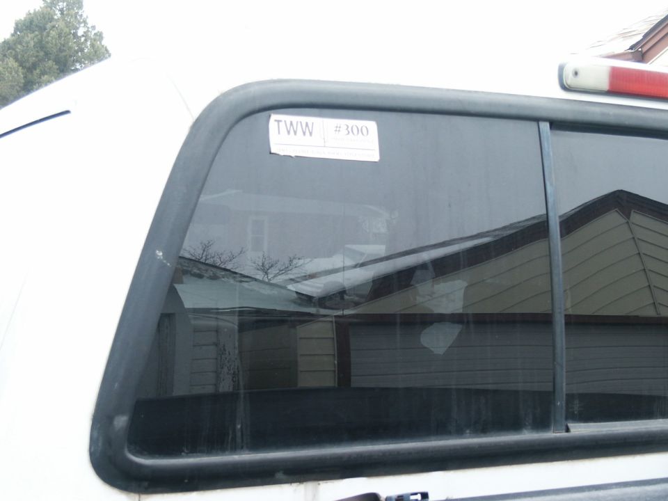 Rear window of a white truck with a sticker that says TWW #300