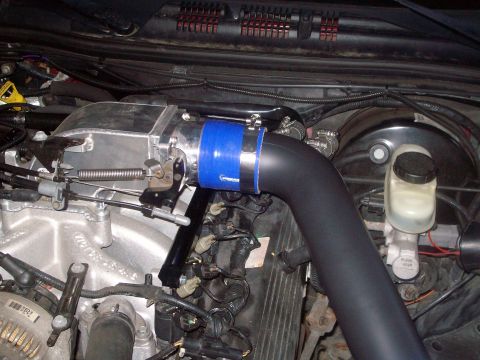 2004 Ford Crown Victoria - Close-up of an engine bay showing an aftermarket intake system and brake fluid reservoir.