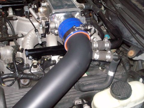 2004 Ford Crown Victoria - Close-up view of an engine's intake tube, a blue and orange silicone coupler and various hoses and wiring.