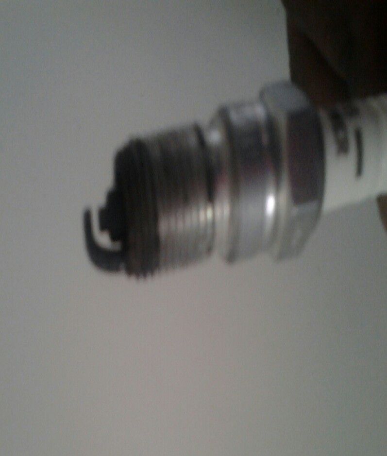 Close-up of a used spark plug with visible wear on the electrode
