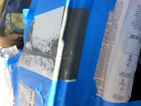 1992 Ford Bronco - A vehicle body panel is taped off and covered with newspaper, showing signs of repair work.