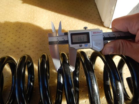 2003 Ford Crown Victoria - hand holds a Mitutoyo digital caliper displaying 16.3 against a black coil spring on a perforated tan pad.