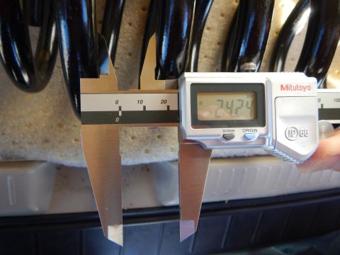 2003 Ford Crown Victoria - Mitutoyo digital caliper showing 74.74 measures the coil pitch of a black coil spring over a tire and liner.