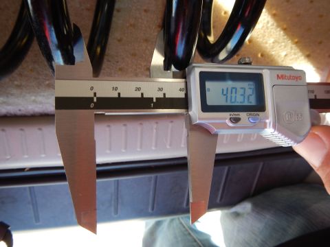 2003 Ford Crown Victoria - Mitutoyo digital caliper reading 40.32 measures the coil spacing of a black coil spring on a tan pad.