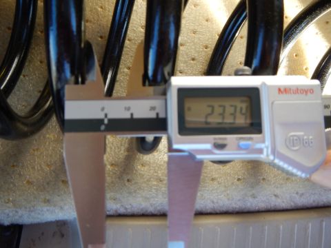 2003 Ford Crown Victoria - Mitutoyo digital caliper showing 23.34 measures the coil spacing of a black coil spring on a perforated tan pad.