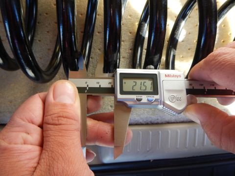 2003 Ford Crown Victoria - Mitutoyo digital caliper held in two hands measures the wire diameter of a black coil spring, displaying 21.51 on its readout.