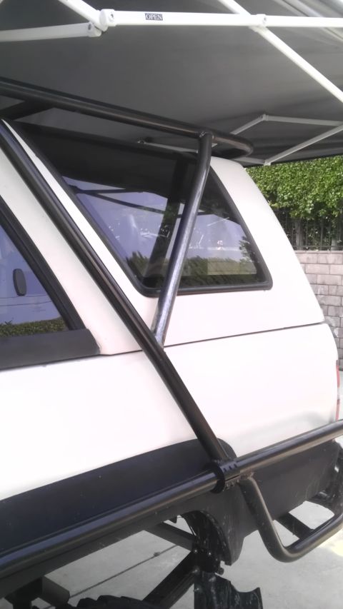 1985 Toyota 4Runner - This white SUV features a black roll cage and an extended awning, partially obscuring the rear windows.