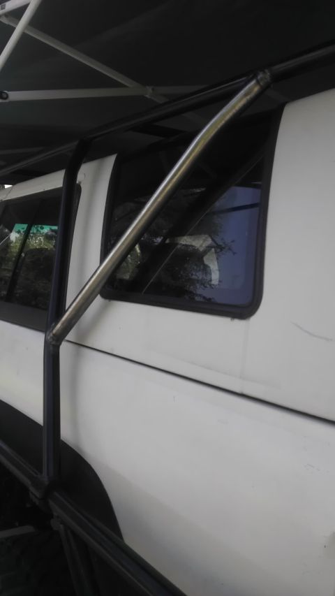 1985 Toyota 4Runner - A white SUV is partially visible with a custom roll cage and roof rack structure attached to its exterior.