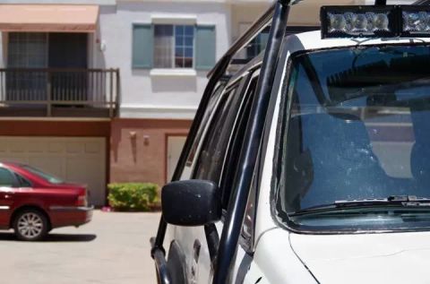 1985 Toyota 4Runner - A white off-road vehicle is parked in front of a building, with a red sedan visible to the left.