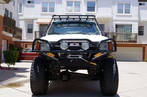 1985 Toyota 4Runner - Front view of a modified white 1985 Toyota 4Runner, equipped with a heavy-duty bumper and roof rack.