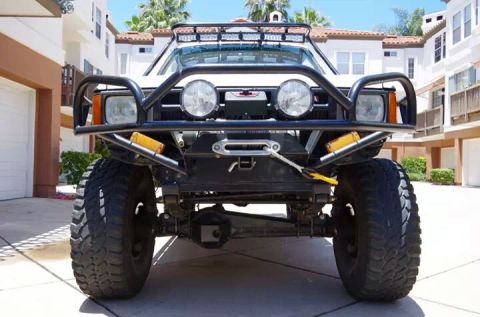 1985 Toyota 4Runner - This heavily modified off-road SUV features a prominent winch, auxiliary lights, and a roof-mounted light bar.