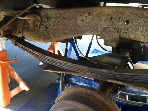 1977 Ford F-350 - Close-up view of a vehicle's rear leaf spring suspension system, supported by jack stands.