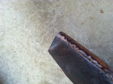 1977 Ford F-350 - A rusted metal part rests on a concrete floor, with a Supermotors.net logo in the corner.