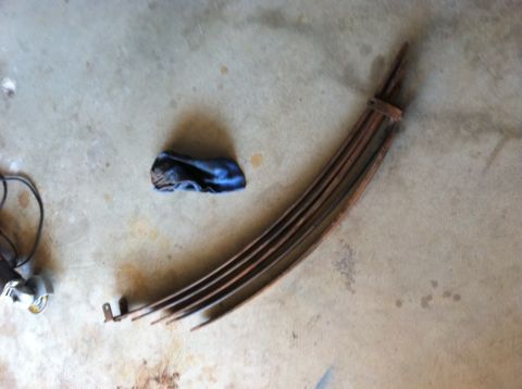 1977 Ford F-350 - Leaf springs are shown on a concrete surface, alongside a blue cloth and a grinder.